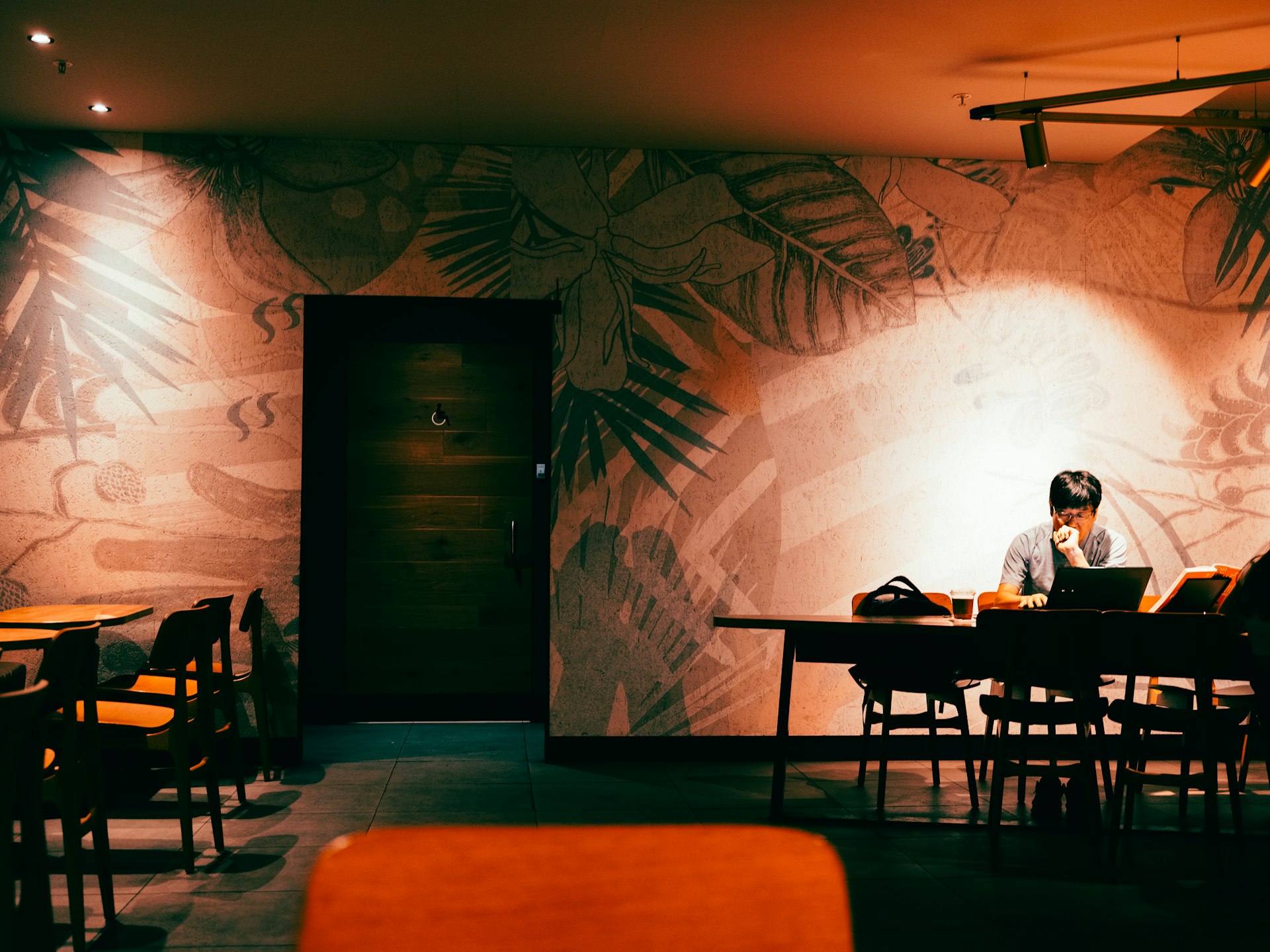 Man working on laptop in dimly lit cafe