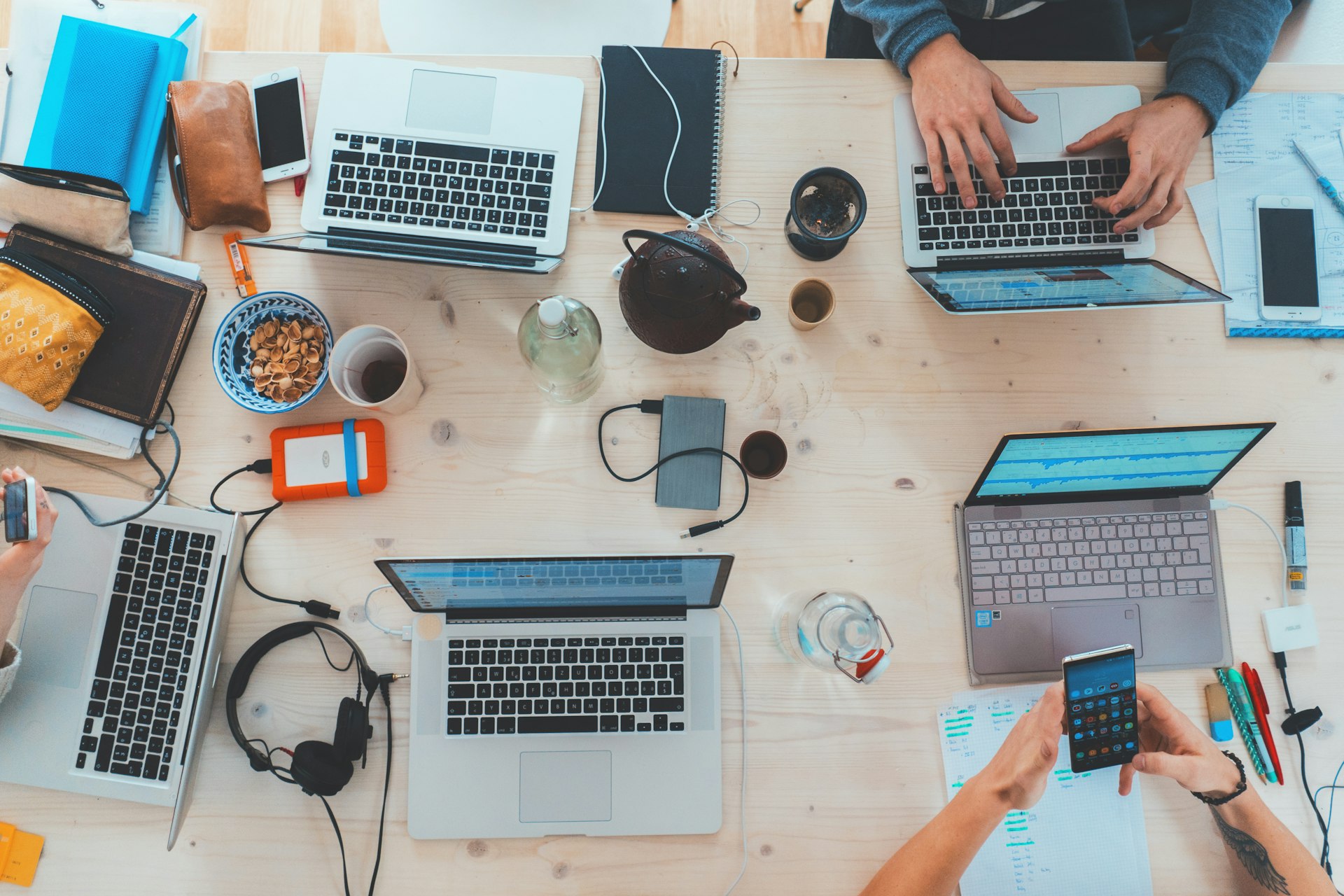 multiple laptops and coffee on a wooden coworking table