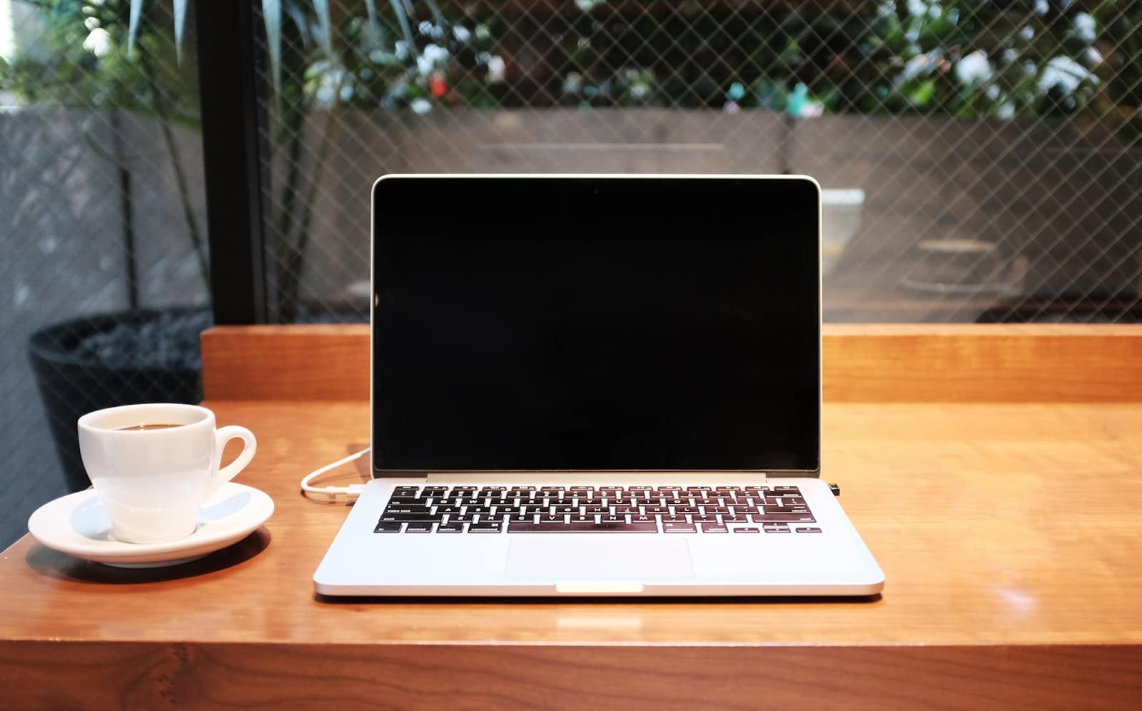A laptop and a coffee on a cafe table, screen dark