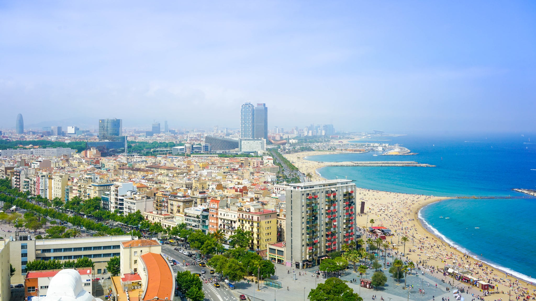 Aerial view of Barceloneta, the Barcelona city beach and the skyline behind it
